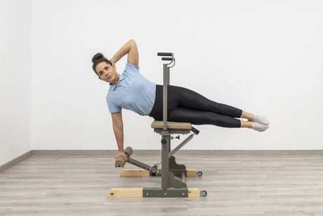  Side view of the HEGREN Pilates Chair TALMA 62CH showcasing its steel frame and beige upholstery.