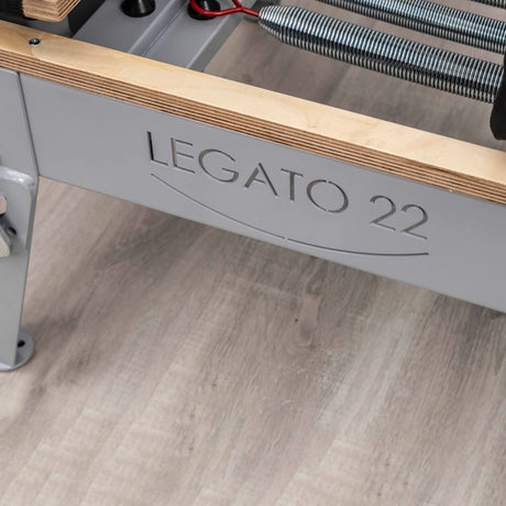  Side view of the HEGREN Pilates Reformer LEGATO 22 showcasing its steel frame and black upholstery.