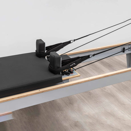  Side view of the HEGREN Pilates Reformer LEGATO 22 showcasing its steel frame and black upholstery.