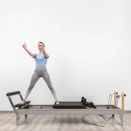  Side view of the HEGREN Pilates Reformer LEGATO 22 showcasing its steel frame and black upholstery.
