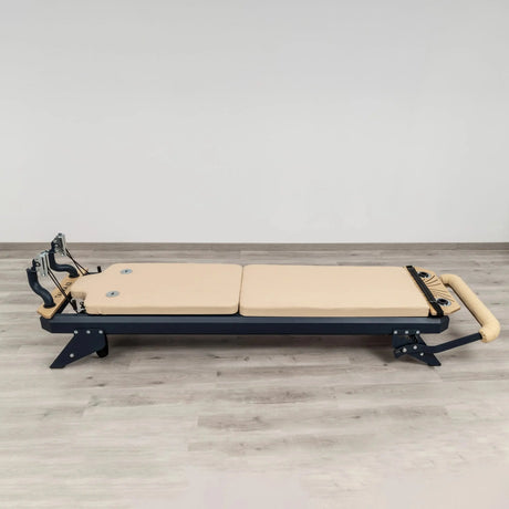 HEGREN Mat Converter TALMA placed on a Pilates Reformer, showcasing its cushioned surface and beige upholstery.