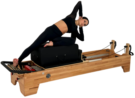 Woman using a Pilates reformer machine on a white background