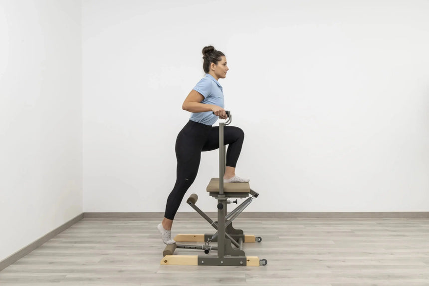  Side view of the HEGREN Pilates Chair TALMA 62CH showcasing its steel frame and beige upholstery.
